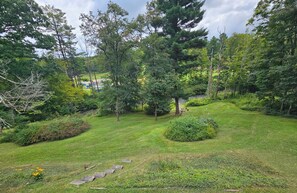 A well-maintained garden with a variety of trees and shrubs, a clear path, and a small pond. - Private, 6-Acre Cottage with Old-Time Fishing Hole! (Friedens)