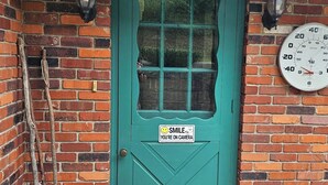 Une porte de couleur turquoise ornée d’un autocollant représentant un visage souriant, une horloge et un paillasson.