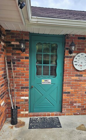 A teal door with a smiley face sticker, a clock, and a doormat. - Private, 6-Acre Cottage with Old-Time Fishing Hole! (Friedens)