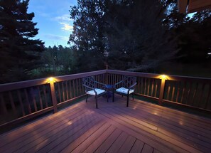 A wooden deck with two chairs and a table, surrounded by a railing and trees. - Private, 6-Acre Cottage with Old-Time Fishing Hole! (Friedens)