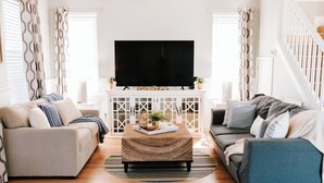Un salon moderne avec deux canapés, une table basse et un téléviseur posé sur un meuble blanc.