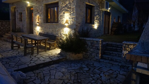 A stone building with a patio, outdoor seating, and a barbecue area.