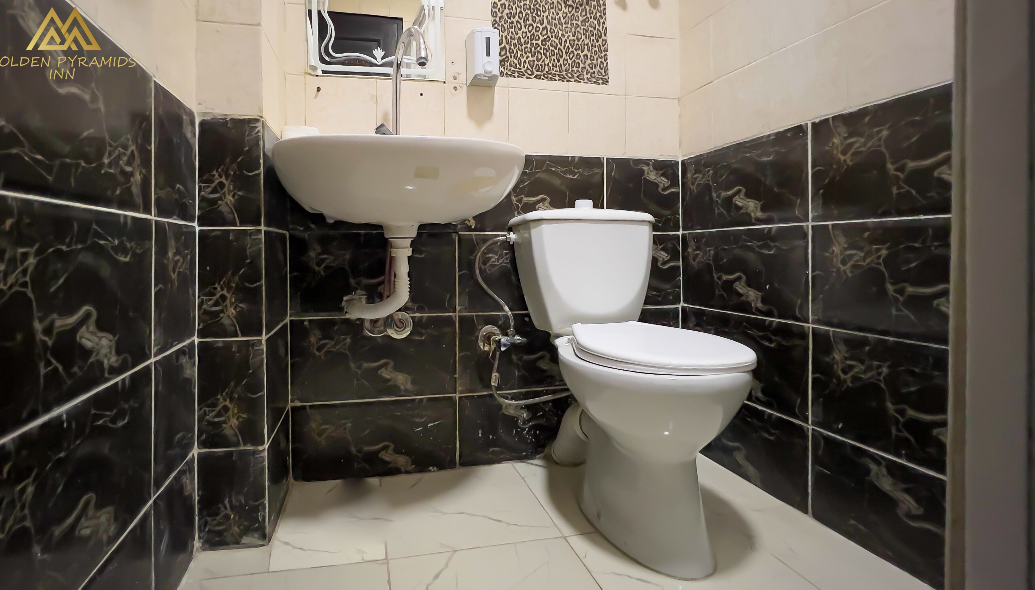 A bathroom with a white sink, toilet, and marble-tiled walls.