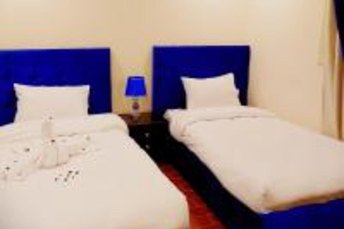 Ein Hotelzimmer mit zwei Betten, einem Nachttisch mit Lampe und einem kleinen Bild an der Wand.