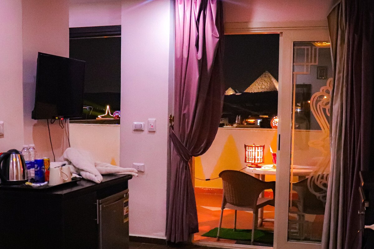 A hotel room with a bed, a desk with a telephone, a chair, and a view of the outside.