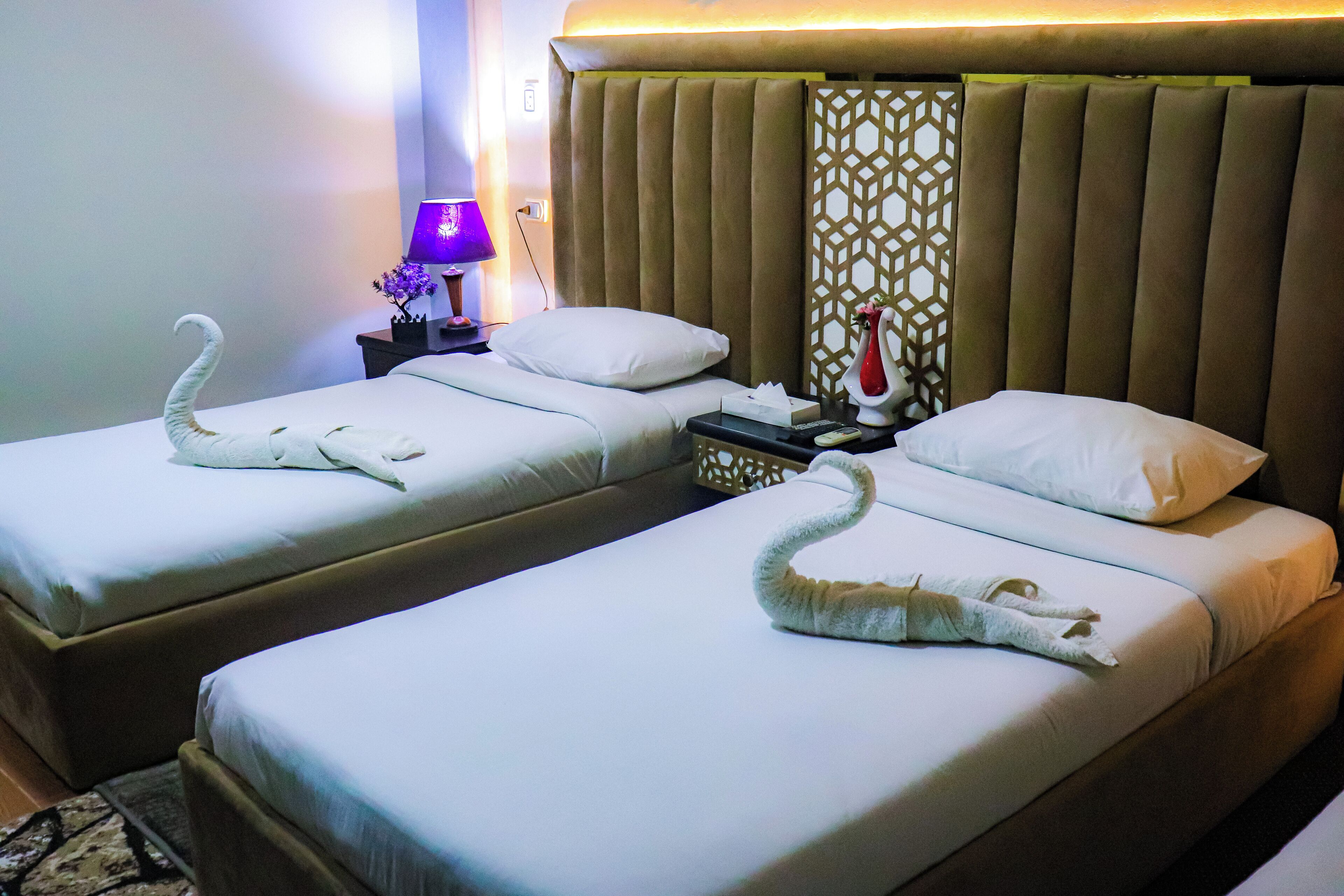 A hotel room with two beds, each adorned with a swan-shaped towel.
