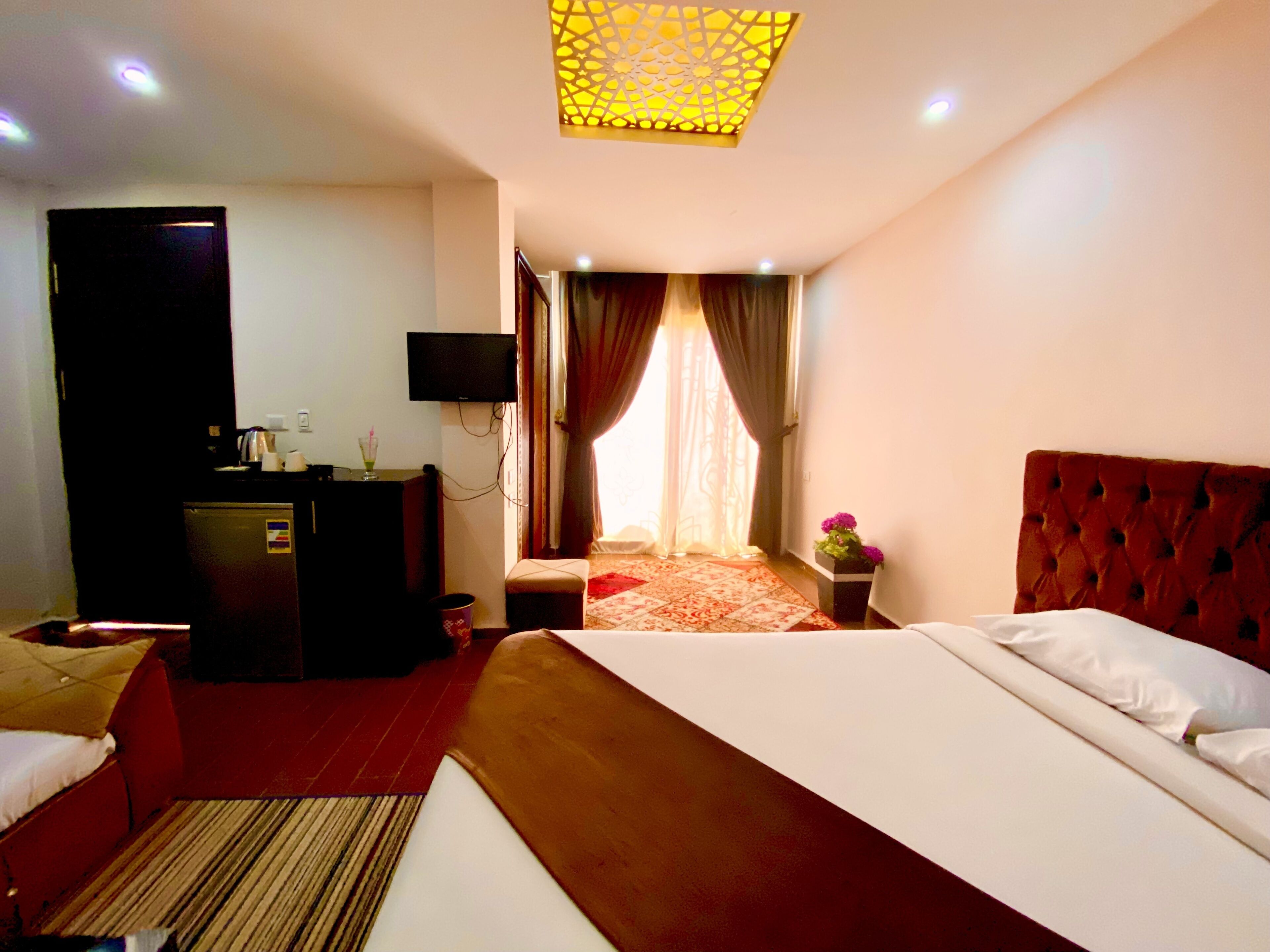 A hotel room with a bed, a desk, a television, and a window with curtains.