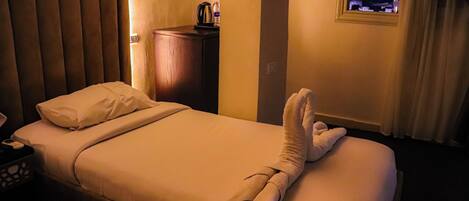 Una camera d'hotel con un letto, un comodino, una lampada, una finestra vista piramide e un asciugamano sul letto.