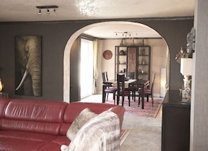 A living room with a red sofa, a dining area with a table and chairs, and a hallway leading to another room. - AlmerimarDuplexlujoo/sea view/JACUZ private / 🆓WIFI/SMART tv / lav-sec🐎⛳️🏄‍♂️ (Almerimar)