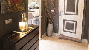 A hallway with a dark wooden dresser, a lit lantern, a decorative vase, and a door with a unique design. - AlmerimarDuplexlujoo/sea view/JACUZ private / 🆓WIFI/SMART tv / lav-sec🐎⛳️🏄‍♂️ (Almerimar)
