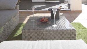An outdoor patio area with a wicker table, a glass of champagne, and a bowl of fruit. - AlmerimarDuplexlujoo/sea view/JACUZ private / 🆓WIFI/SMART tv / lav-sec🐎⛳️🏄‍♂️ (Almerimar)
