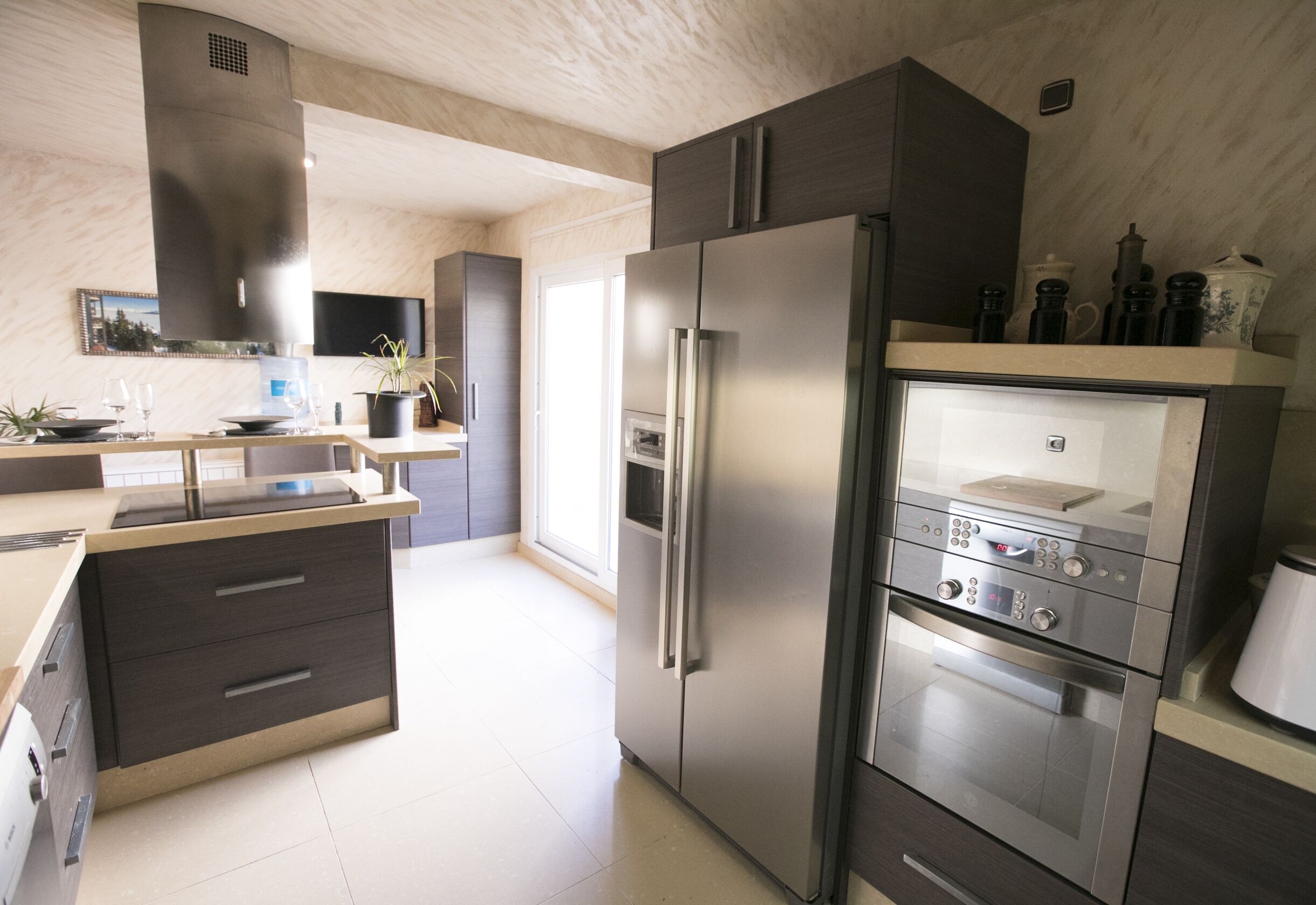 Een moderne keuken met roestvrijstalen apparatuur, een ingebouwde oven en een groot kookeiland met spoelbak.