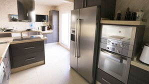A modern kitchen with stainless steel appliances, a built-in oven, and a large island with a sink. - AlmerimarDuplexlujoo/sea view/JACUZ private / 🆓WIFI/SMART tv / lav-sec🐎⛳️🏄‍♂️ (Almerimar)