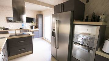 Een moderne keuken met roestvrijstalen apparatuur, een ingebouwde oven en een groot kookeiland met spoelbak.