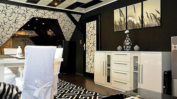 Une cuisine moderne avec un crédence à motifs noir et blanc, un meuble blanc doté de tiroirs et un vase décoratif posé sur le plan de travail.