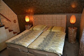 A bedroom with a large bed, two bedside lamps, a wooden headboard, and a small wooden ladder against the wall. - Apartment Sweden House (Eschede)