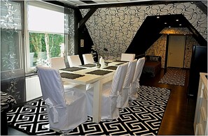 A dining area with a table set for six, white chairs, and a patterned floor. - Apartment Sweden House (Eschede)