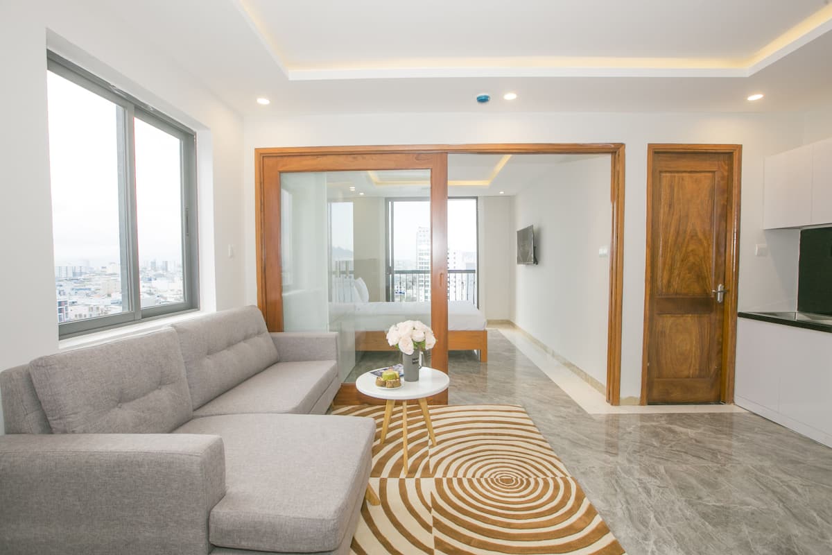 Un salon moderne avec un canapé gris, une table basse ornée d’un vase et un tapis à motifs.