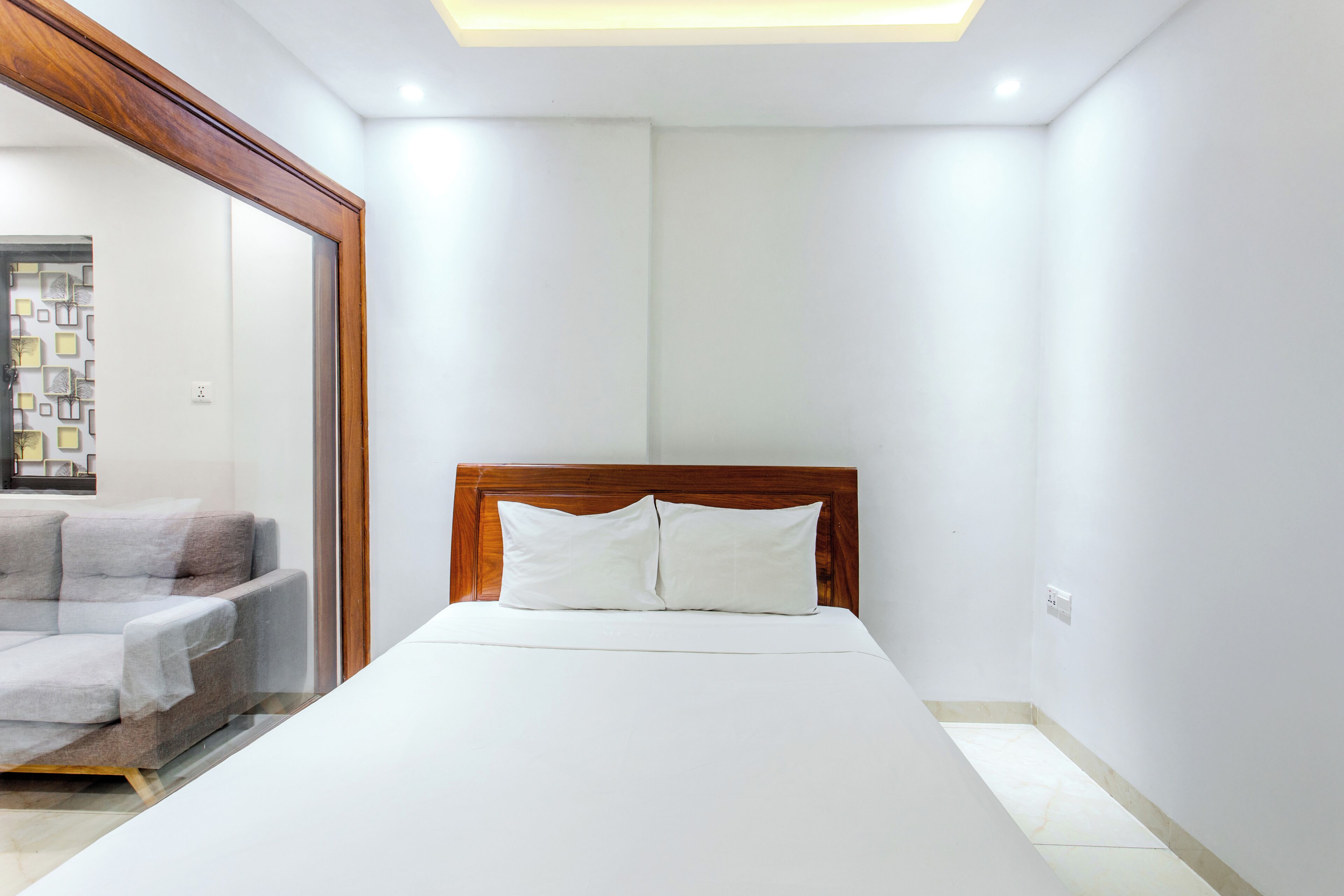 Un dormitorio con una cama, cabecera de madera y pared blanca.