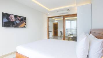 A hotel room with a large bed, a flat-screen TV mounted on the wall, and a sliding glass door leading to a balcony.