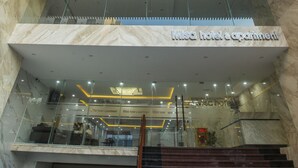 Un hotel moderno con una entrada destacada, fachada de vidrio y una escalera visible que conduce a la recepción.