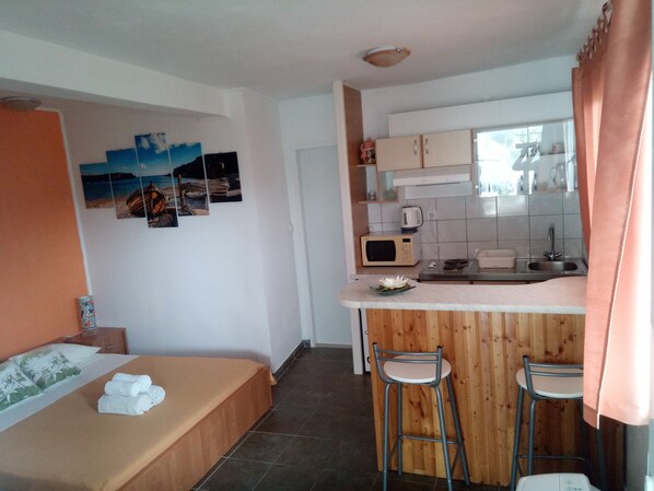 A compact kitchen with a microwave, sink, and wooden bar stools.