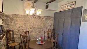 A dining area with a stone wall, wooden chairs, a round table, and a chandelier.