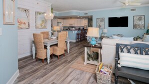 Un salon avec des meubles en osier, un coin repas, une cuisine et un ventilateur de plafond.