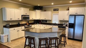 A modern kitchen with white cabinetry, a stainless steel refrigerator, a granite island with bar stools, and a sign that says "life is good". - 2/2 Condo on Lake Hamilton - Great Location! 10% discount on 7 night rental (Hot Springs)