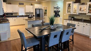A modern kitchen with white cabinetry, a central island, and a dining area with grey upholstered chairs. - 2/2 Condo on Lake Hamilton - Great Location! 10% discount on 7 night rental (Hot Springs)