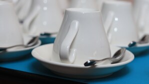 A row of white ceramic cups and saucers on a blue tablecloth.