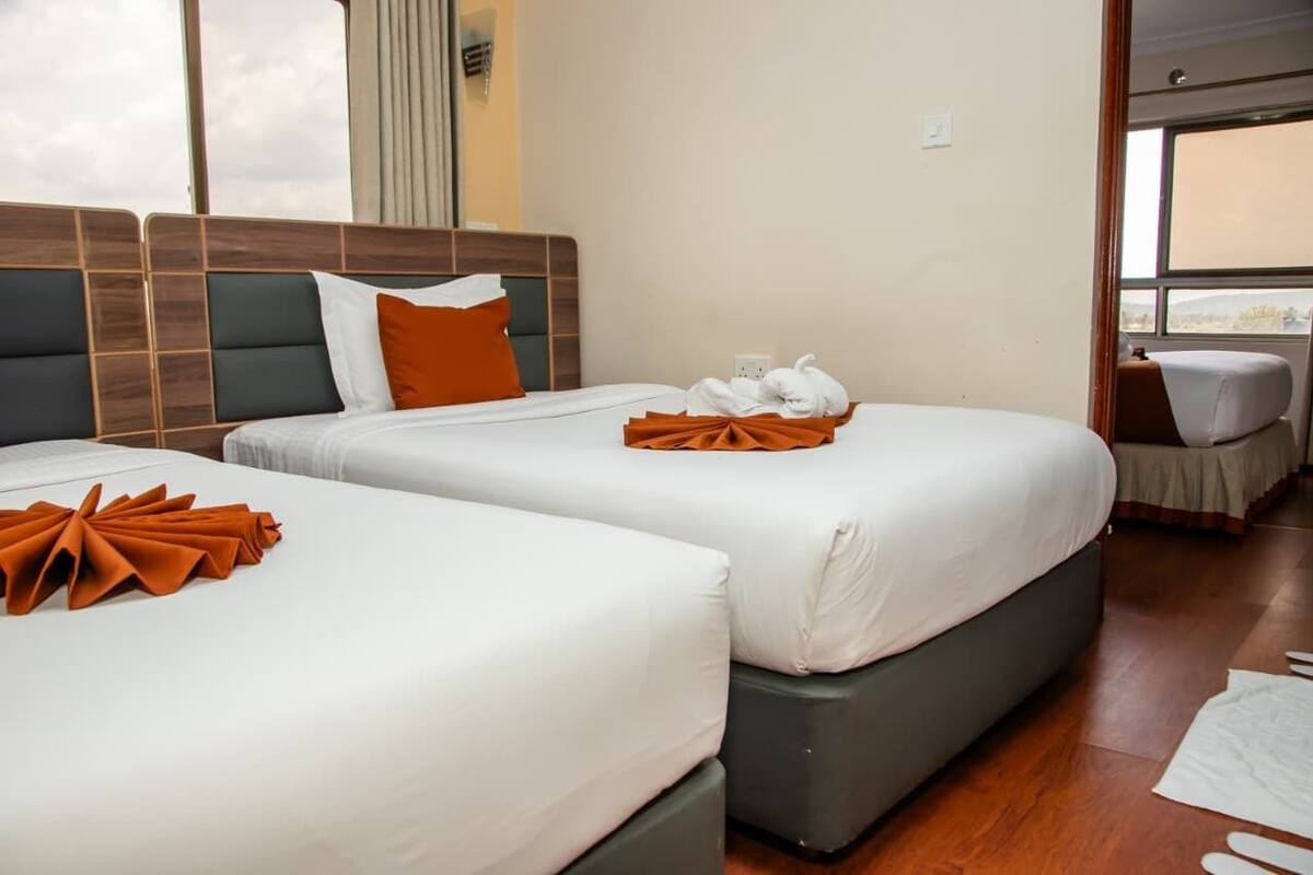 A hotel room with two beds, a view through the window, and a small seating area.