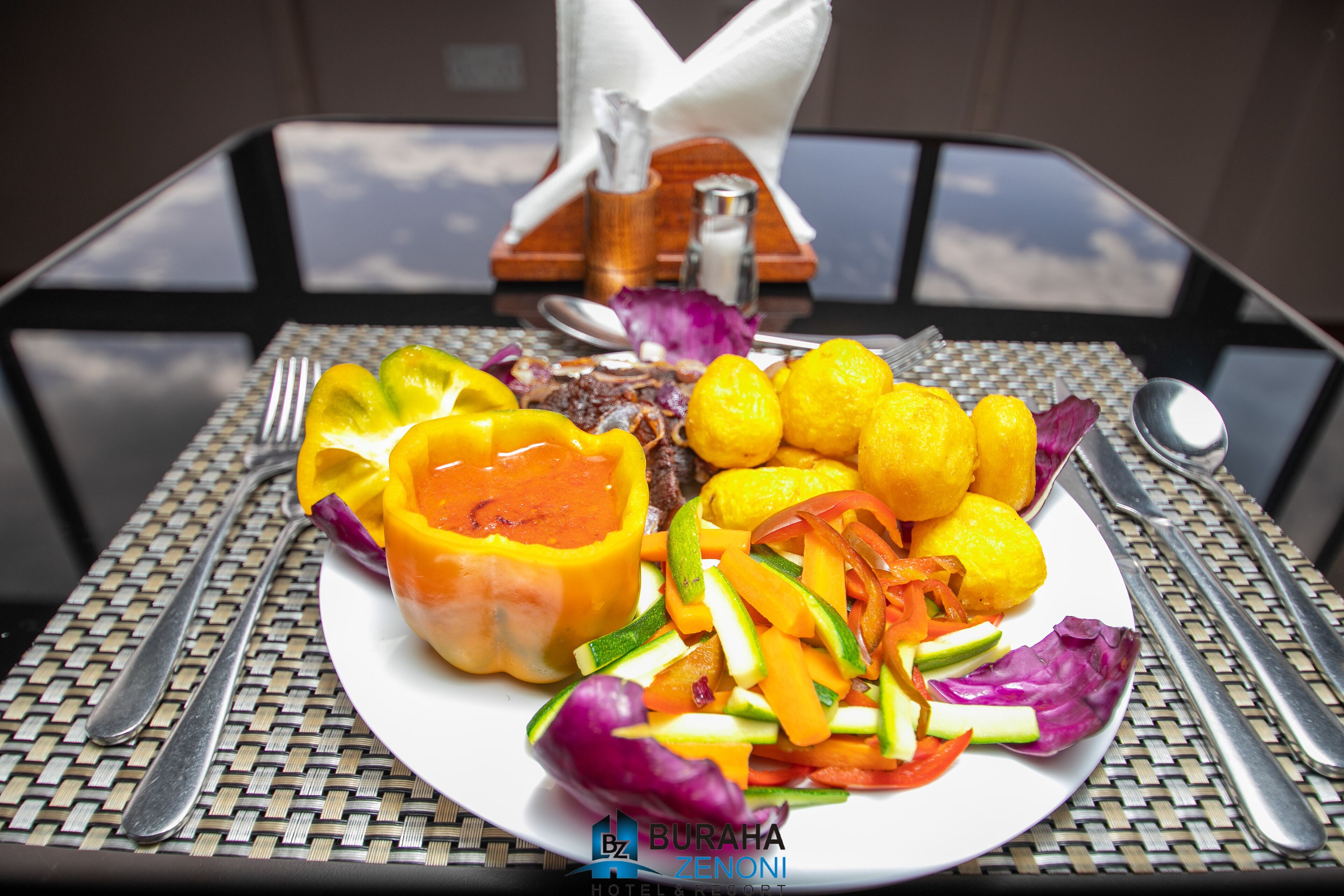 Un plato de comida con pimientos, limones y ensalada sobre una mesa con un mantel tejido.