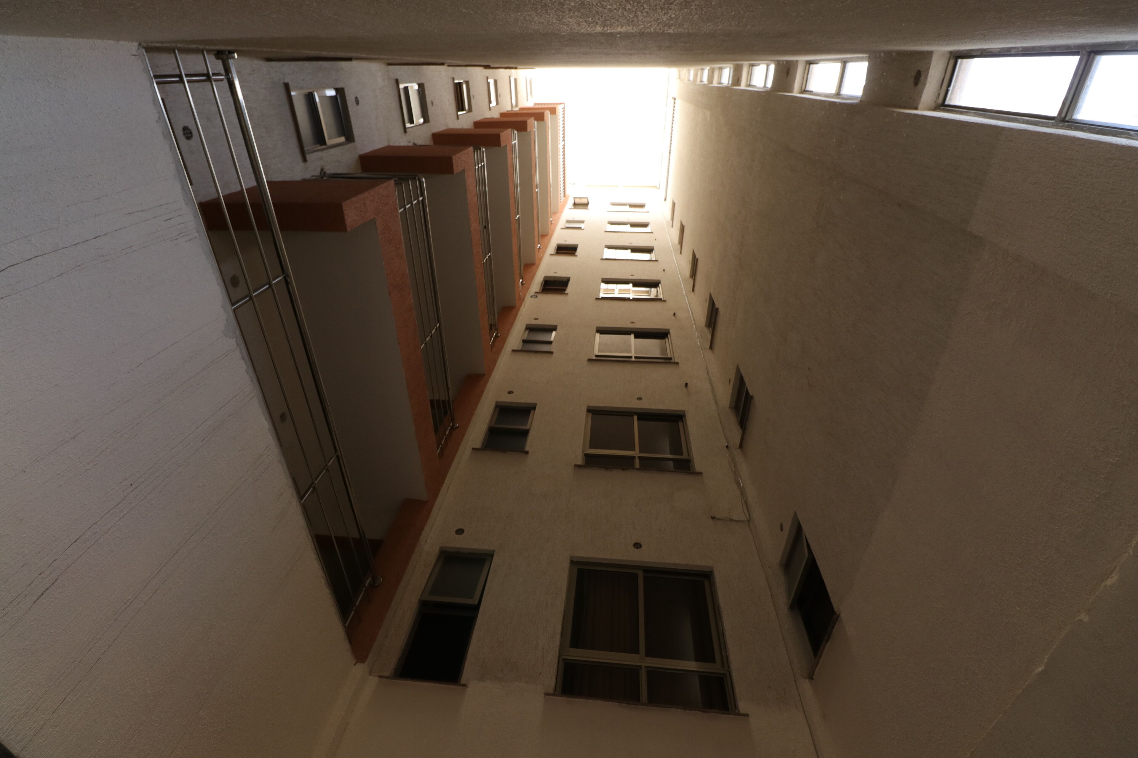 A corridor with multiple windows and doors, leading to individual rooms.