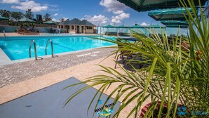 A swimming pool with lounge chairs and umbrellas, surrounded by a landscaped area.
