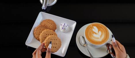 A table with a plate of cookies and a cup of coffee.
