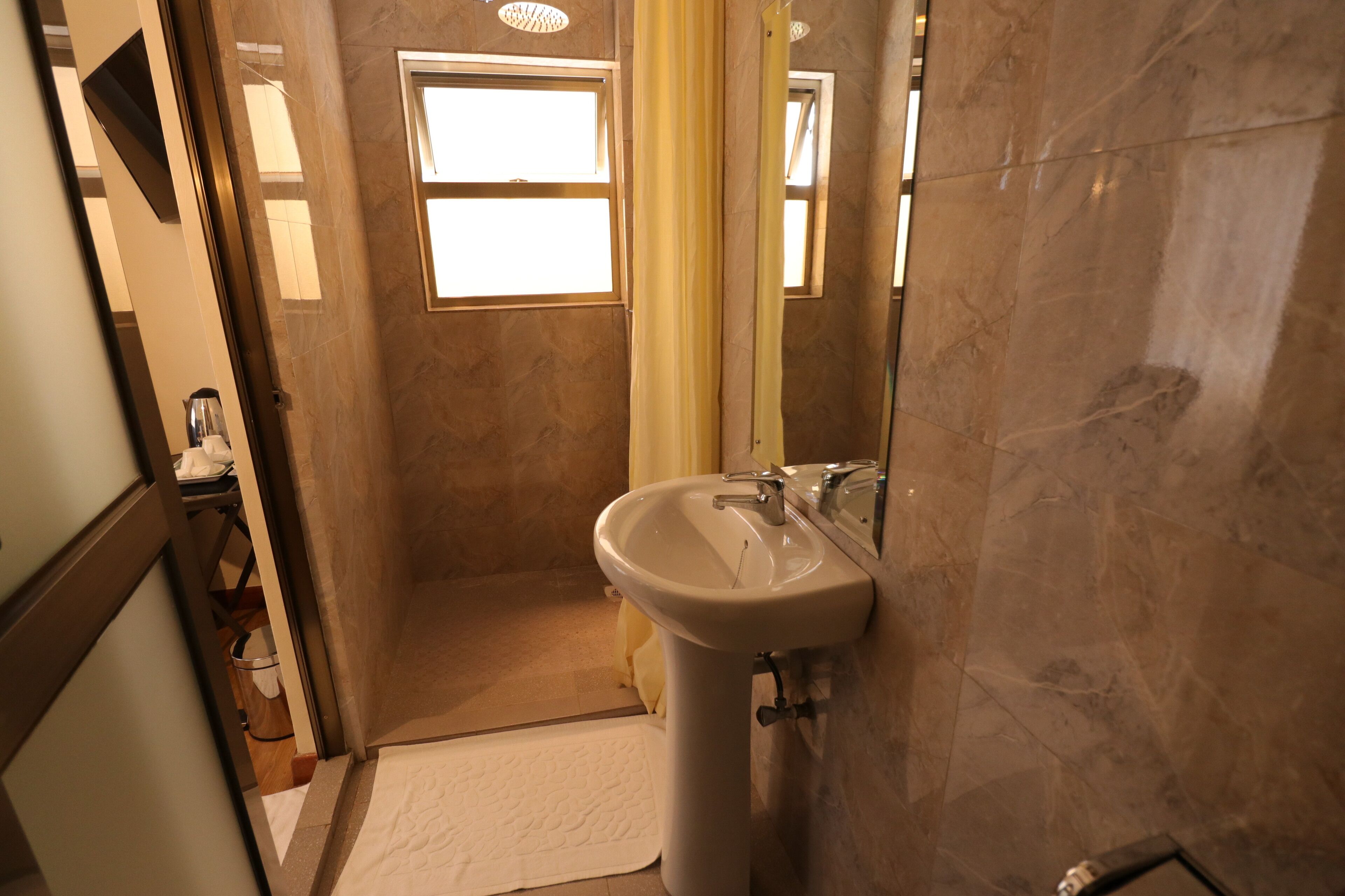 A bathroom with a sink, mirror, and shower area.