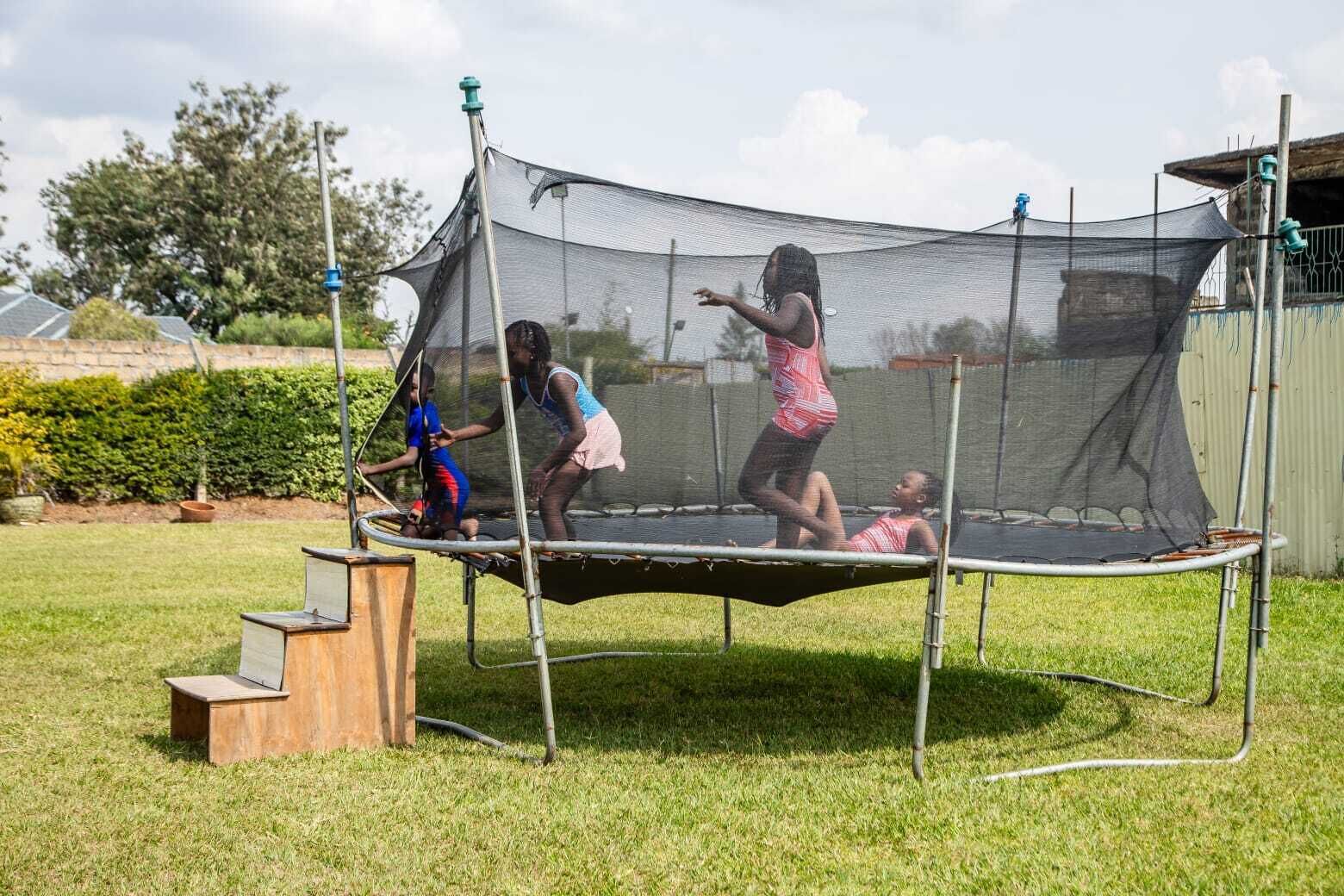 A trampoline with a safety net in a grassy outdoor area.