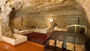 A cave-like room with a sofa, a bed, and a lamp.