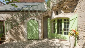 A stone building with a green door and window, a stone staircase, and a potted plant.