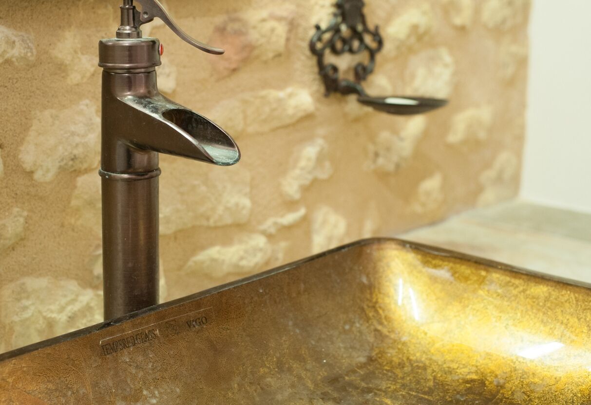 A metallic faucet with a lever handle and a rectangular sink with a reflective surface.