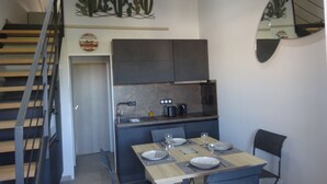 Une cuisine moderne avec des meubles de couleur sombre, une table à manger dressée avec des assiettes et des verres, et un escalier doté d’une rampe.