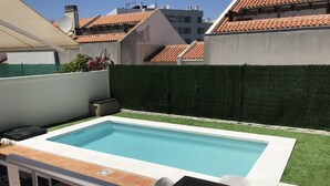 A rectangular swimming pool with a tiled deck, surrounded by a green hedge and a white wall. - Private pool beach. Sohail Castle (Fuengirola)