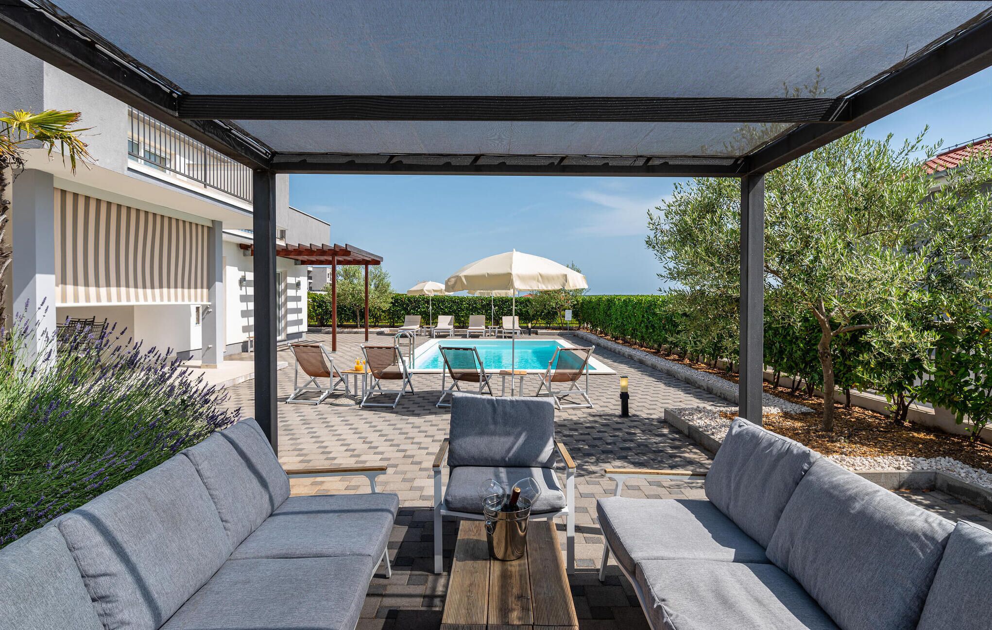A covered outdoor area with a pool, lounge chairs, and a sofa.