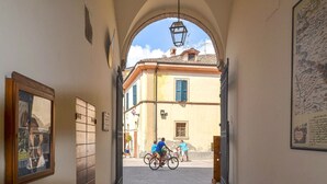 An arched passageway leading to a street with buildings, a map on the wall, and bicycles. - Soc.Agr.IL VERDE s..s (Apecchio)