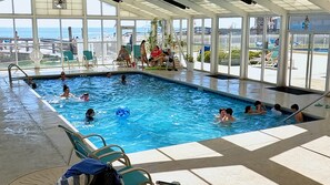 An indoor swimming pool with clear views of the ocean through large windows.