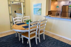A dining area with a round table, white chairs, and a blue rug.