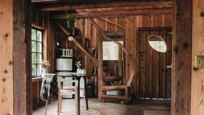 Interior rústico de madera con comedor, escalera y vista por una ventana.