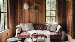 Una habitación acogedora con un sofá de cuero, una manta blanca y una mesa de centro de madera con libros y una bandeja.