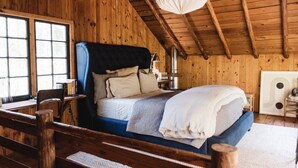 Un dormitorio acogedor tipo cabaña de madera con una cama grande, un escritorio y una ventana.